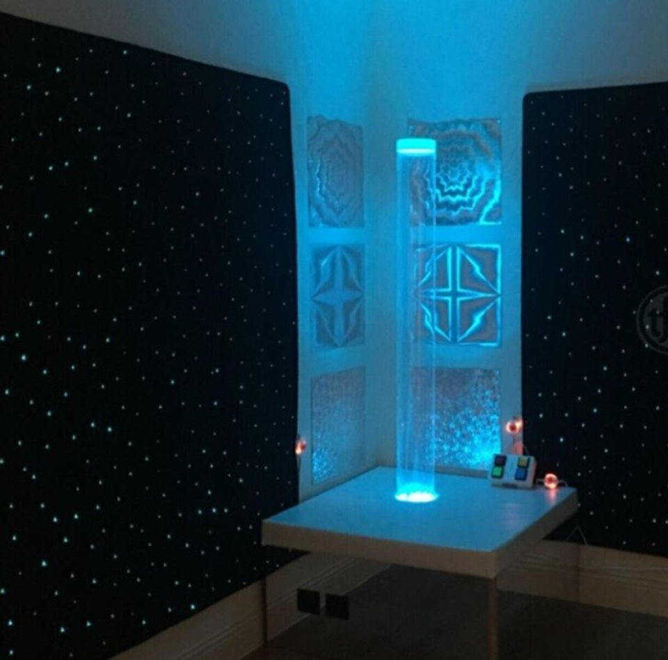 Fiber optic starfield carpet glowing with color-changing light points in a dark sensory room
