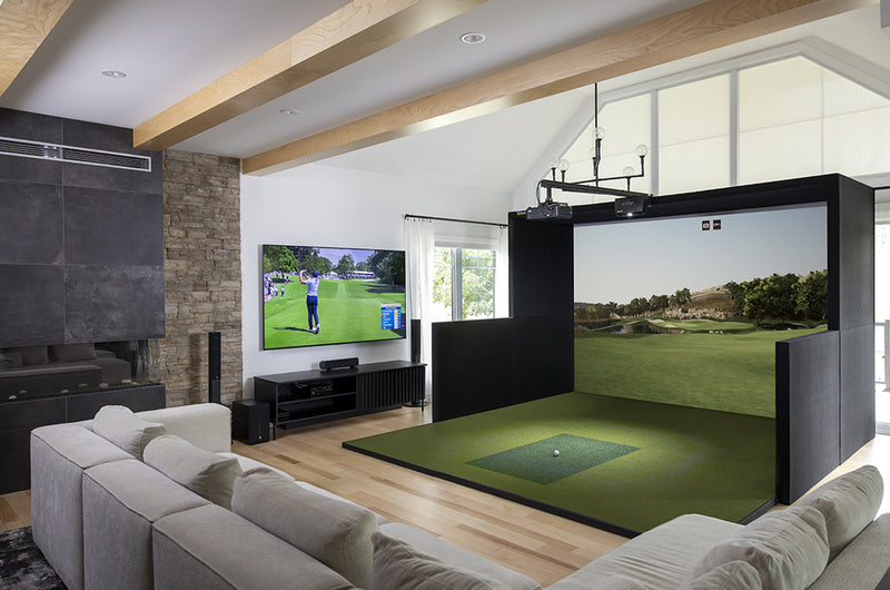 Modern living area with golf simulator enclosure, stone fireplace, and sectional sofa