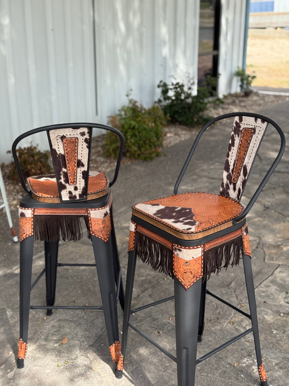 Set of 2 Alamo Saddlery 30 inch black swivel bar stools with hand-tooled leather and cow suede fringe - side view