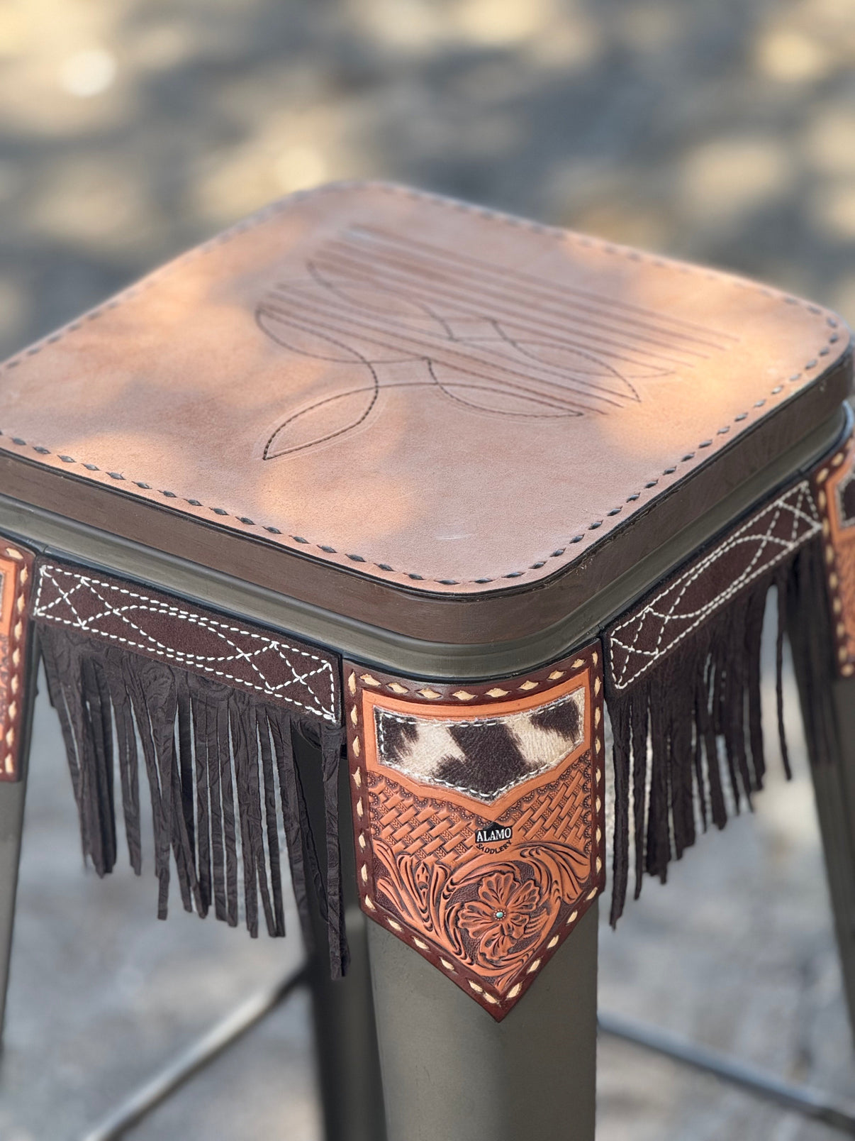 Alamo Saddlery 30 inch black bar stool with golden cowboy stitch leatherwork and fringe - front view