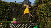 Girl jumping high on the Springfree 8ft Compact Round Trampoline