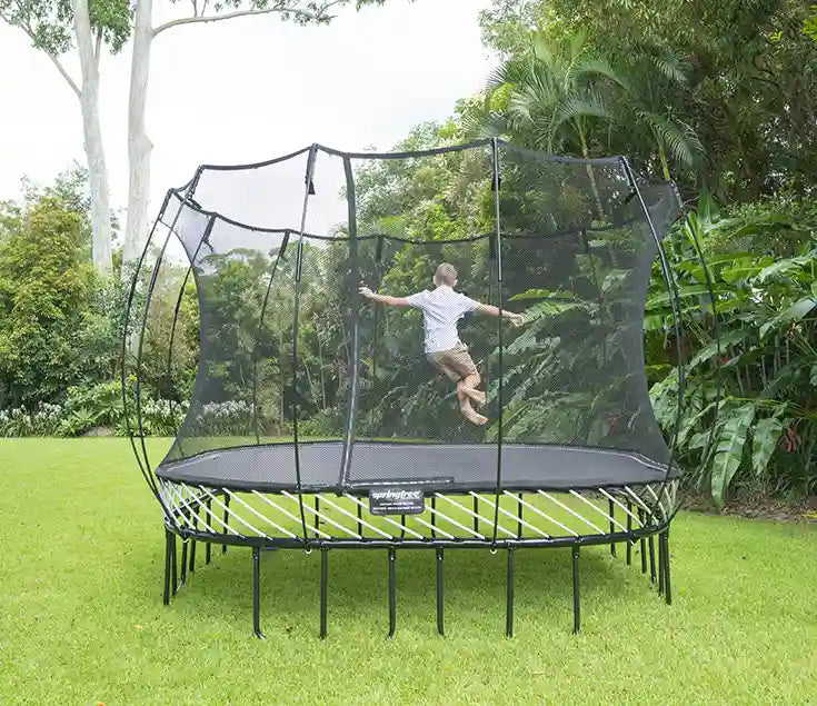 Young boy jumping on the Springfree Large Square Trampoline outdoors