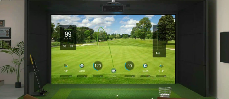 Golf simulator room with framed certificates, indoor plant, and virtual golf course displayed on large screen