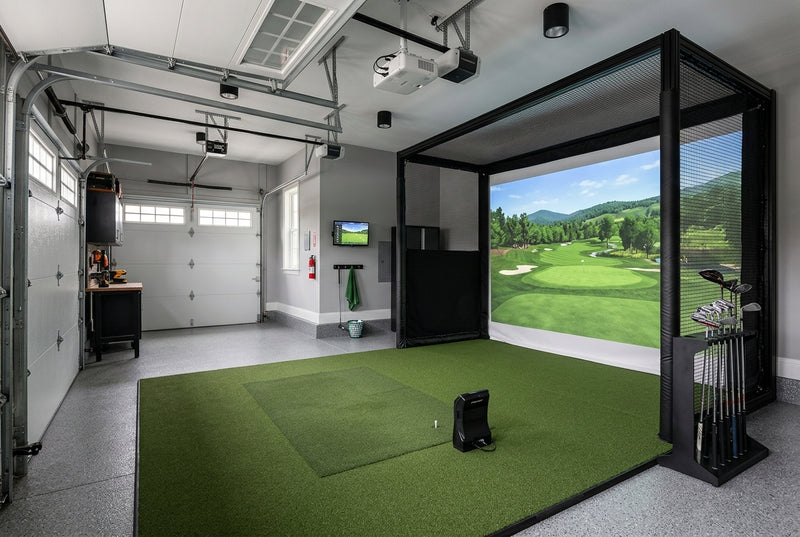Garage converted into golf simulator with enclosure, impact screen, turf mat, and launch monitor